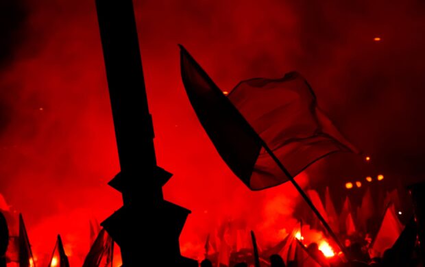 people raising flags near bonfire