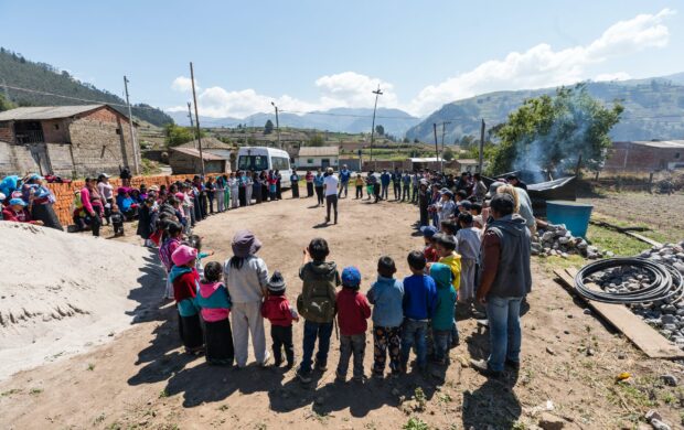 people standing forming circle near house under blue sky during daytime