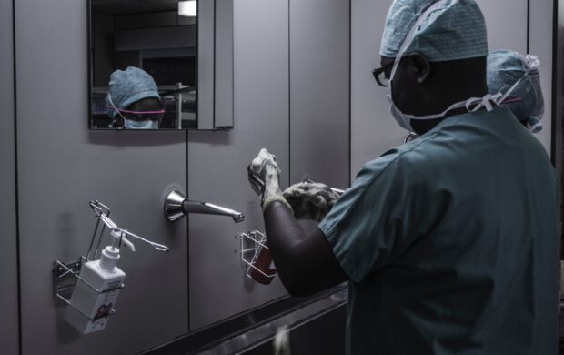 man wearing surgical suit near mirror