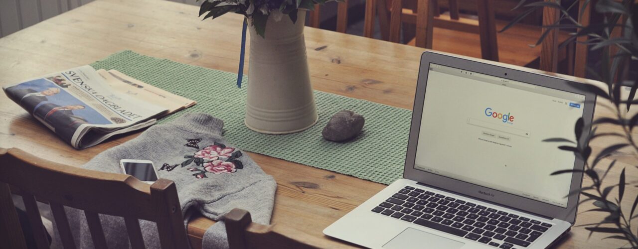 laptop on top of table beside vase of flowers