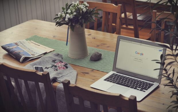 laptop on top of table beside vase of flowers