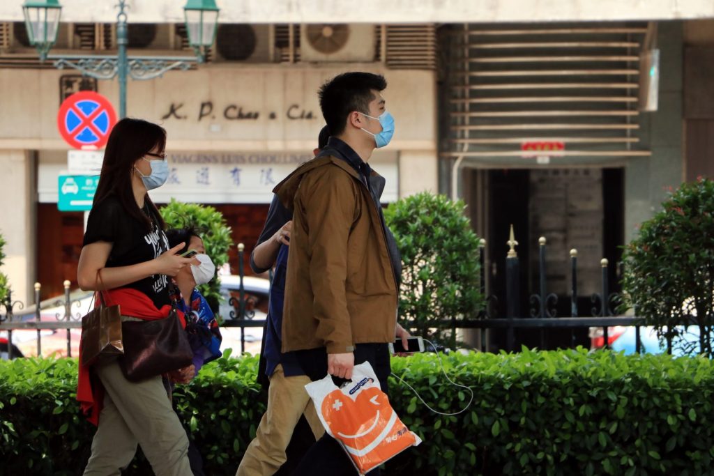 man in brown coat holding red tote bag