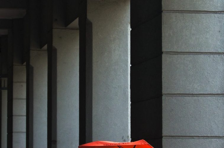 women's holding umbrella beside post
