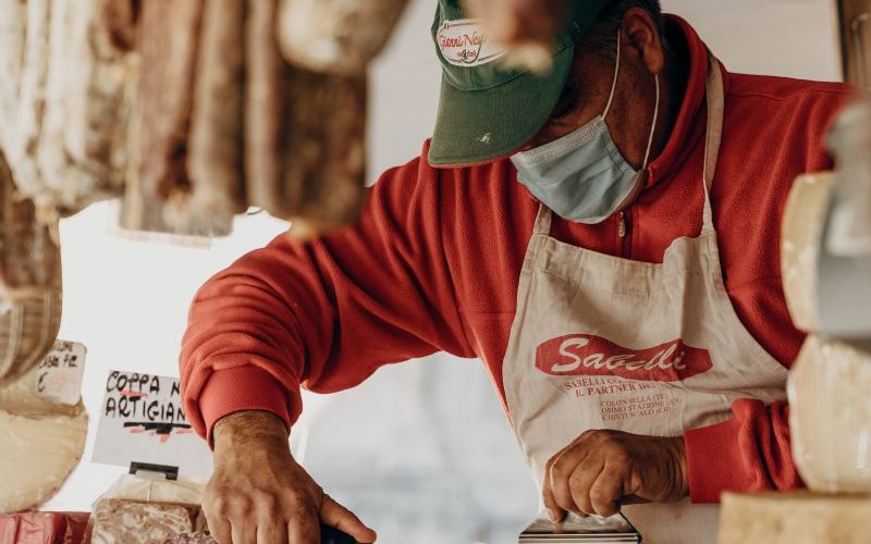 person in red and white long sleeve shirt slicing meat