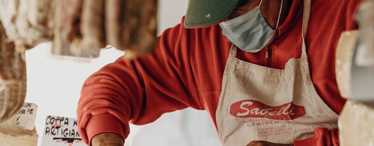 person in red and white long sleeve shirt slicing meat