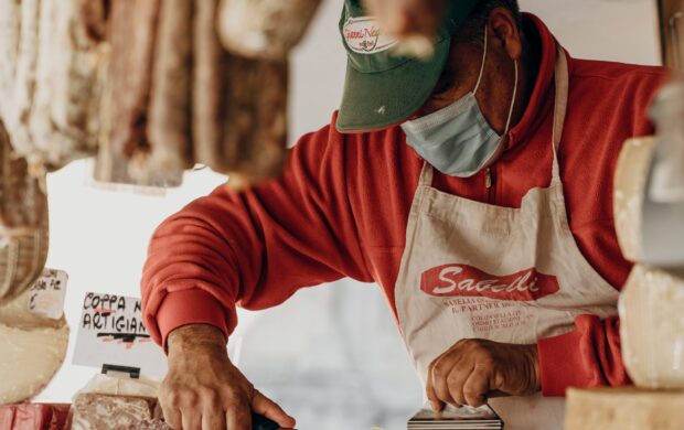 person in red and white long sleeve shirt slicing meat