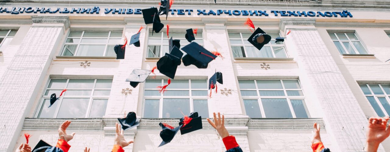 group of fresh graduates students throwing their academic hat in the air