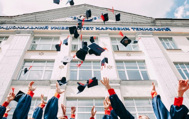 group of fresh graduates students throwing their academic hat in the air