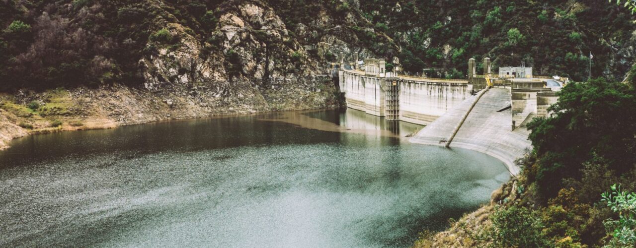 body of water in the middle of hills and concrete wall