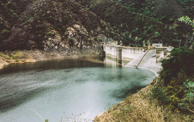 body of water in the middle of hills and concrete wall