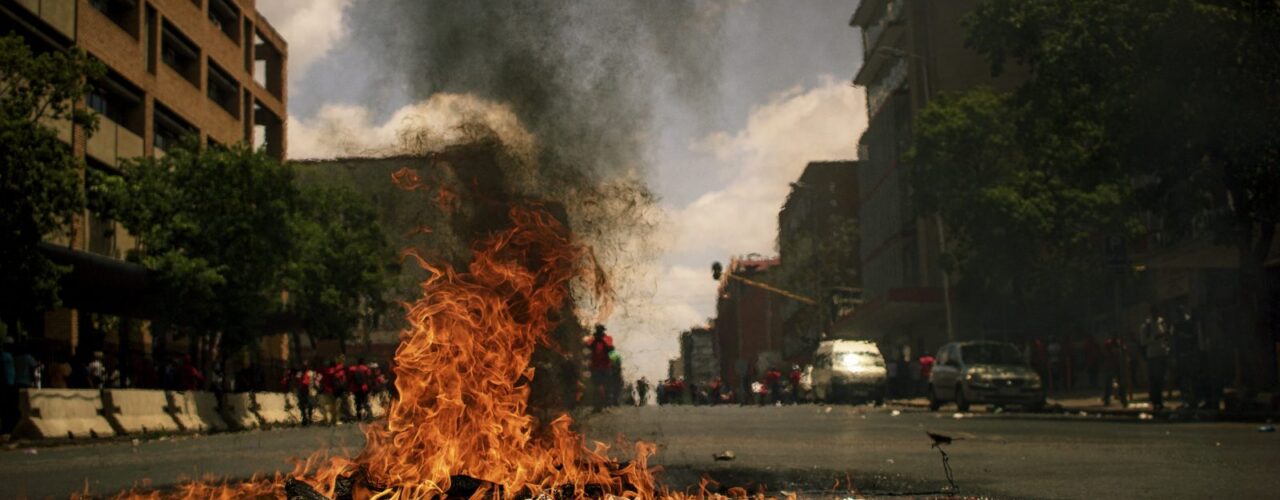 fire burning on the road with high rise buildings during daytime photography