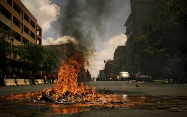 fire burning on the road with high rise buildings during daytime photography