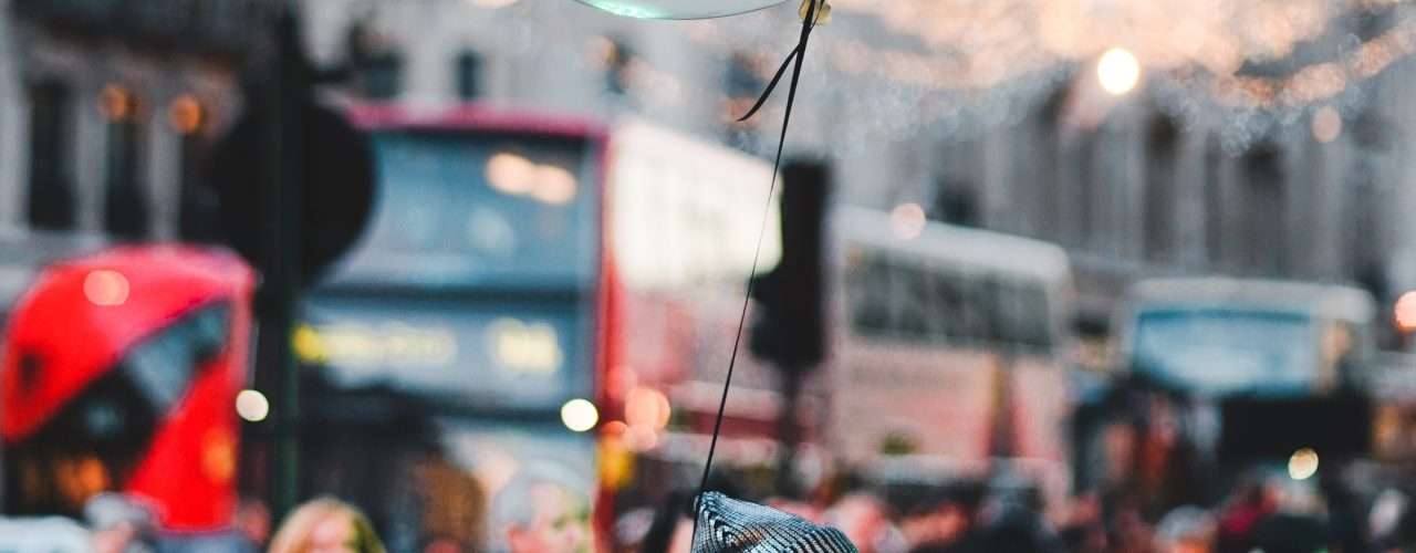 woman walking on street with people holding balloon at daytime