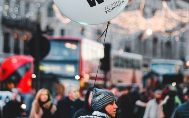 woman walking on street with people holding balloon at daytime