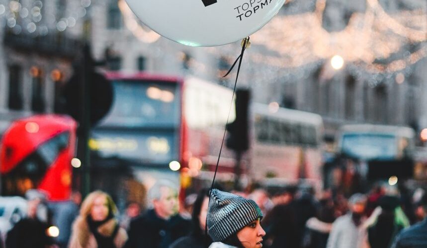 woman walking on street with people holding balloon at daytime