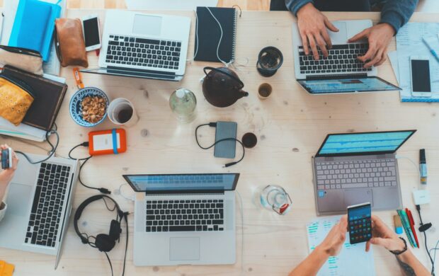 people sitting down near table with assorted laptop computers