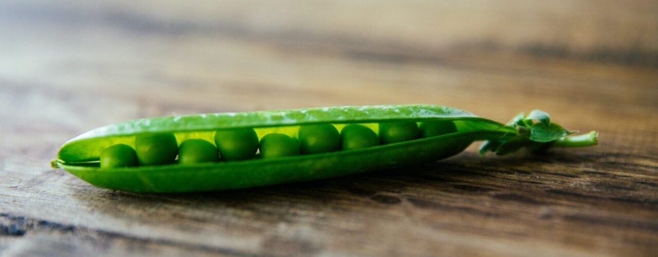 shallow focus photography of green pea on brown wooden surface