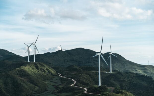 white wind turbines on green grass field under white cloudy sky during daytime