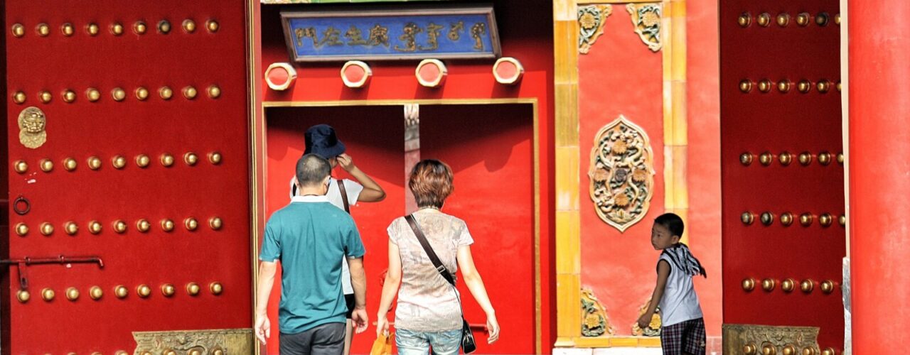 three people walking toward red building