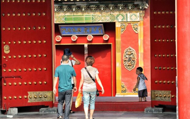 three people walking toward red building