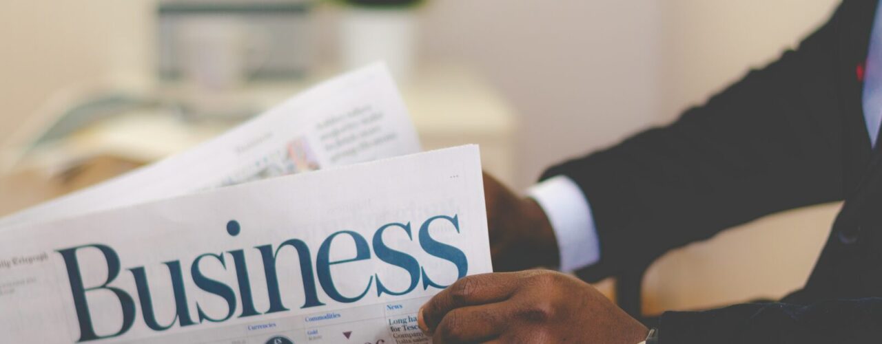 person wearing suit reading business newspaper