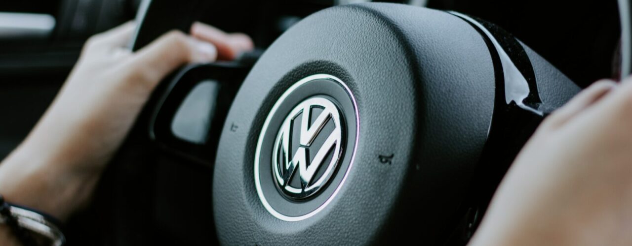 person holding black Volkswagen steering wheel in closed-up photo