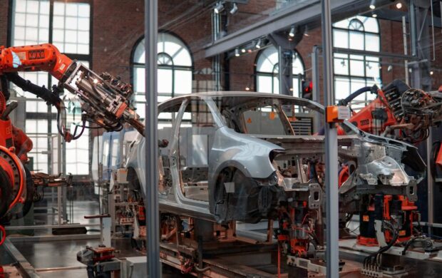 gray vehicle being fixed inside factory using robot machines