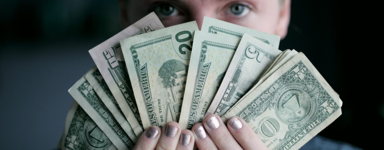 person holding fan of U.S. dollars banknote