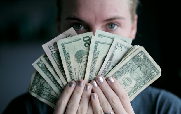 person holding fan of U.S. dollars banknote