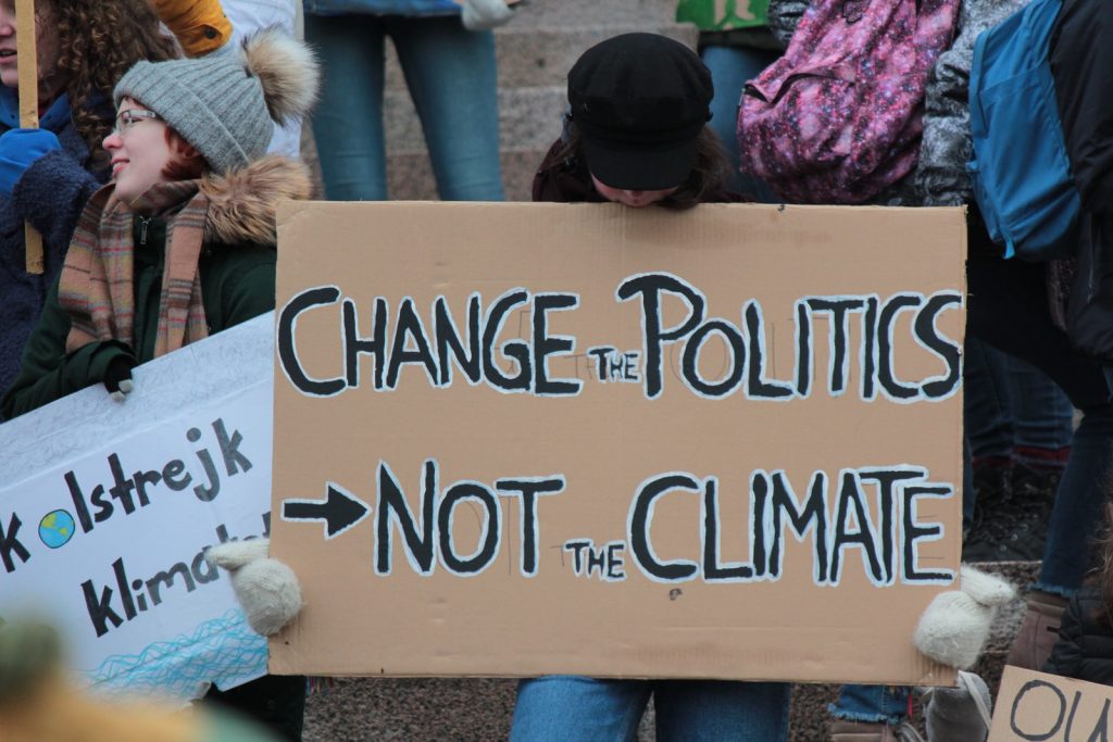 person holding change the politics not the climate printed board