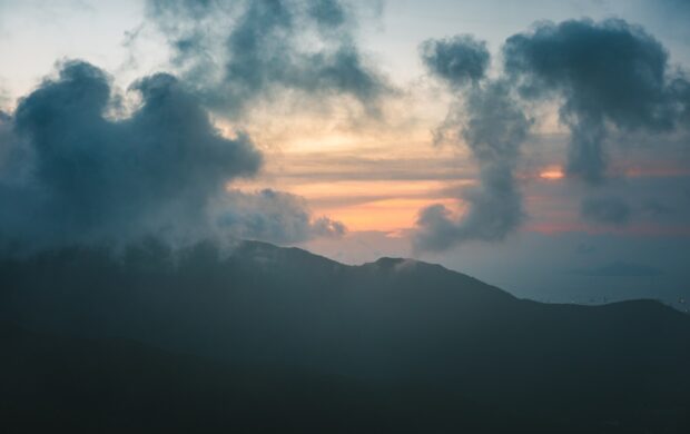 silhouette of mountain under cumulus clouds