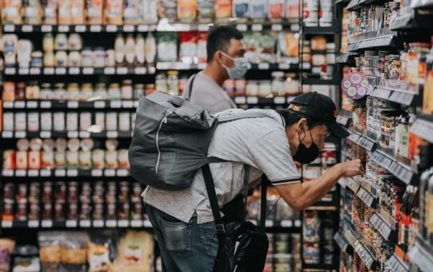 man in gray polo shirt and blue denim jeans standing on grocery store