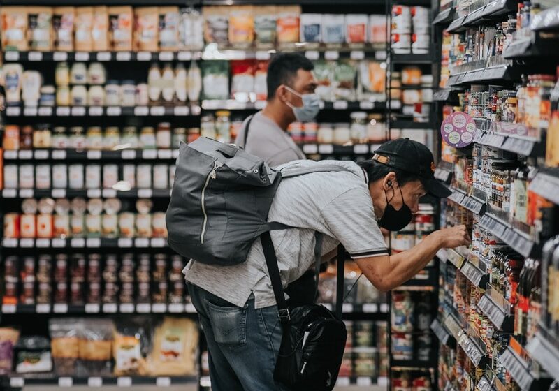 man in gray polo shirt and blue denim jeans standing on grocery store