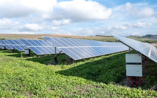 blue solar panels on green grass field under white clouds and blue sky during daytime