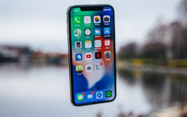 silver iPhone X floating over open palm