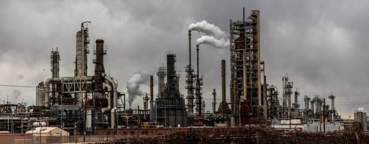 factories with smoke under cloudy sky