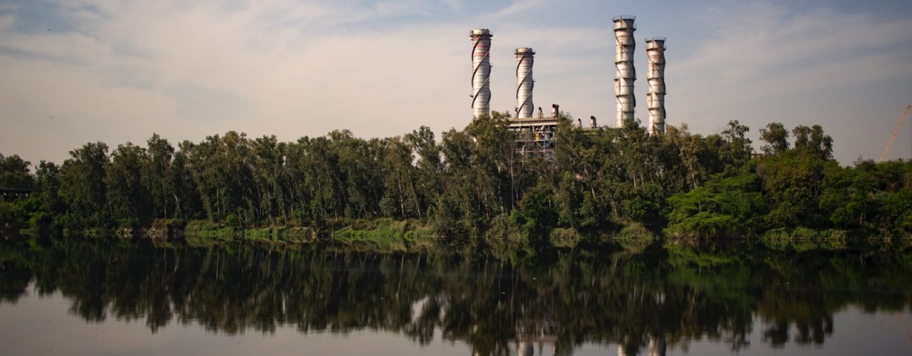 reflection of building with towers and surrounded by trees on body of water during daytime