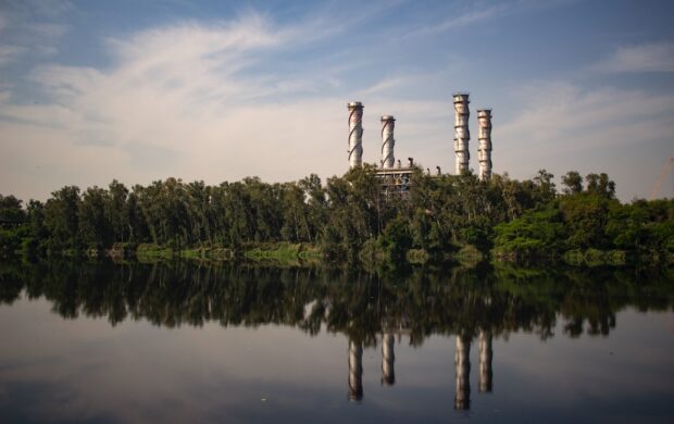 reflection of building with towers and surrounded by trees on body of water during daytime