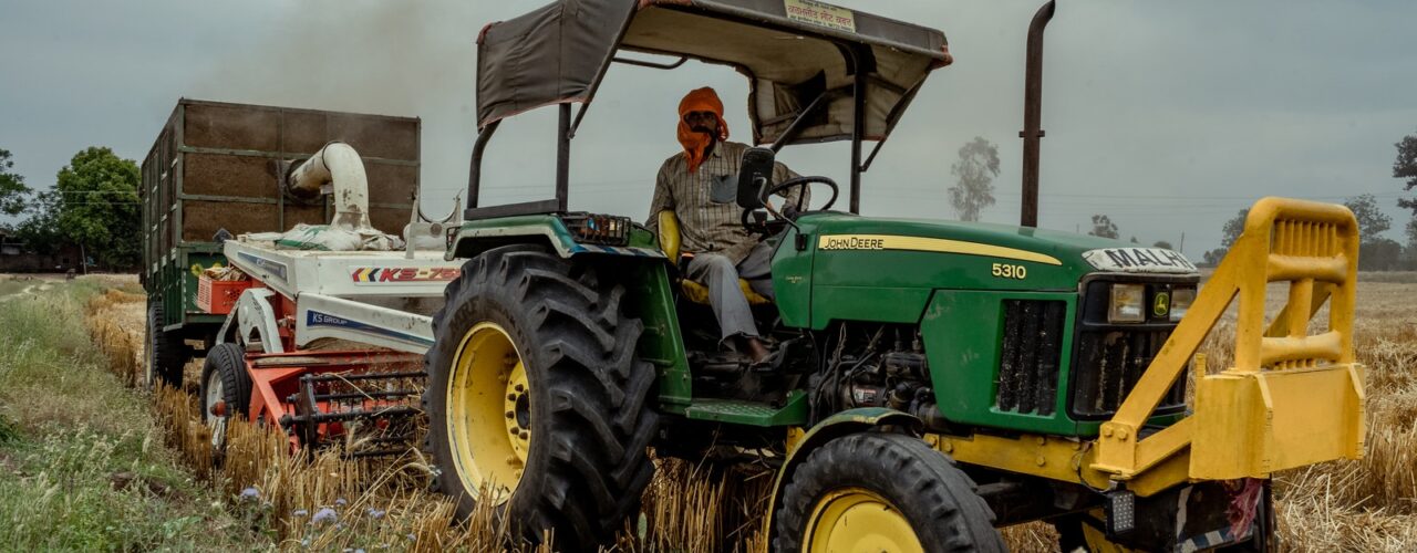 green and yellow tractor on brown grass field under gray sky during daytime