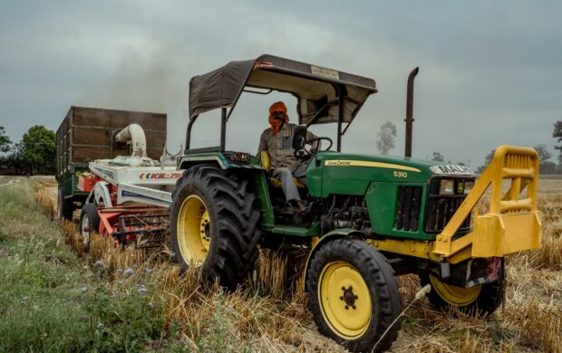 green and yellow tractor on brown grass field under gray sky during daytime