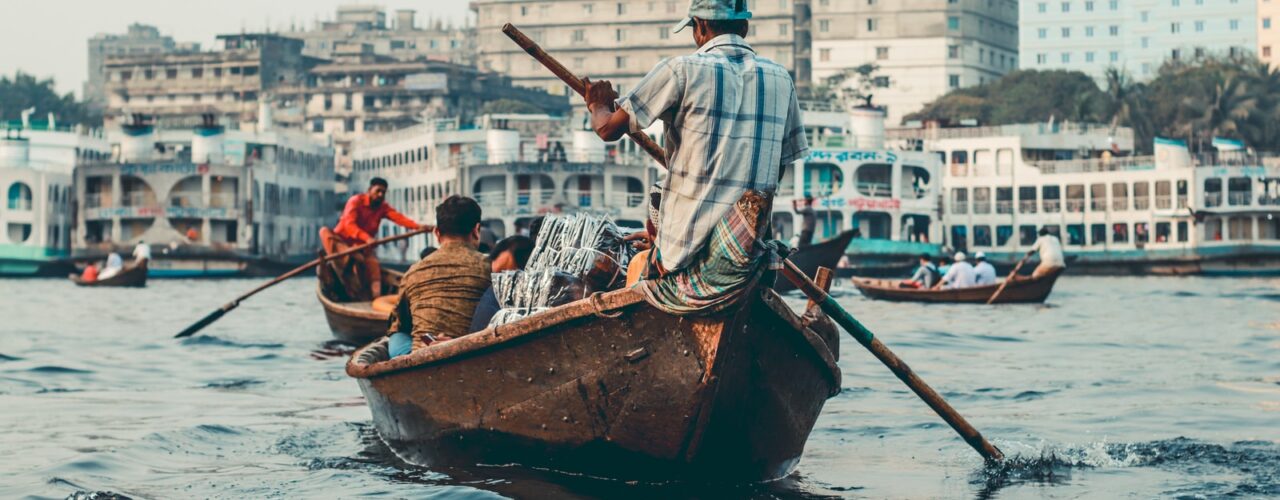 man in blue and white stripe shirt riding on brown boat during daytime