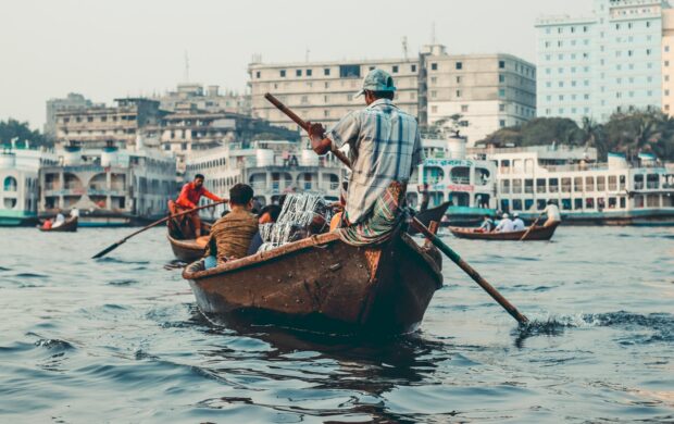 man in blue and white stripe shirt riding on brown boat during daytime