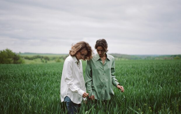 man and woman holding hands while walking on green grass field during daytime