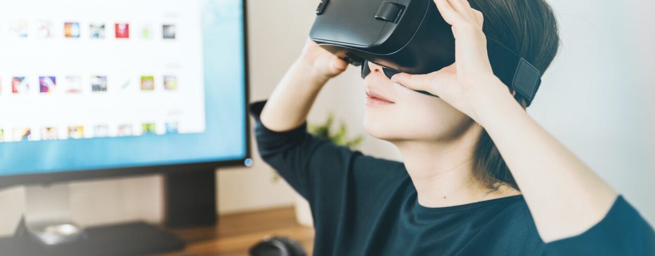 woman using black VR headset beside computer