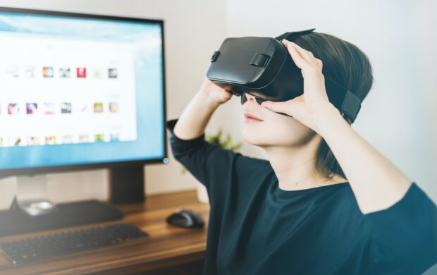 woman using black VR headset beside computer