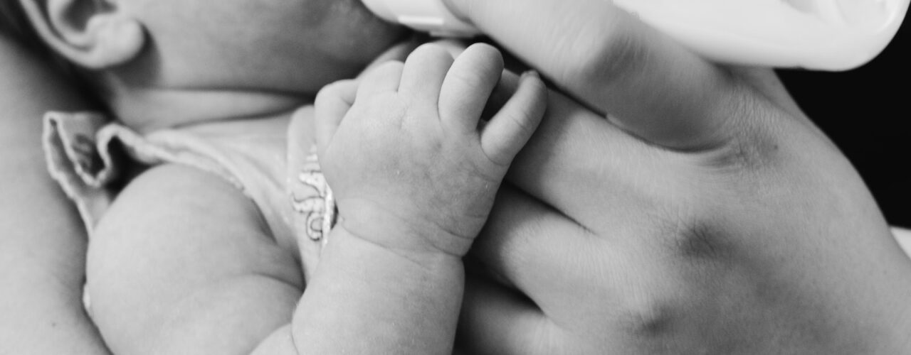 grayscale photo of baby feeding