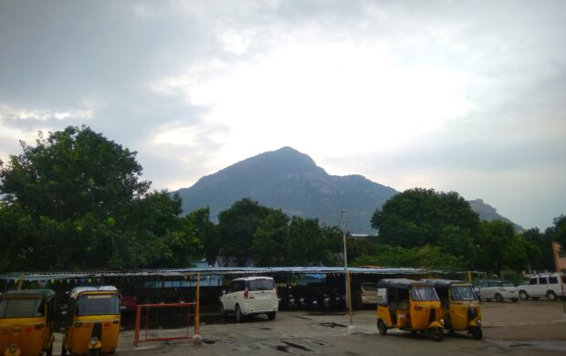 a parking lot with several buses parked in front of a mountain