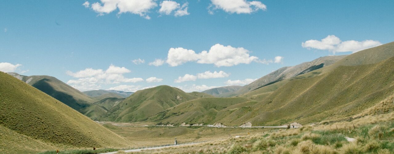 green mountain under white clouds and blue sky during daytime