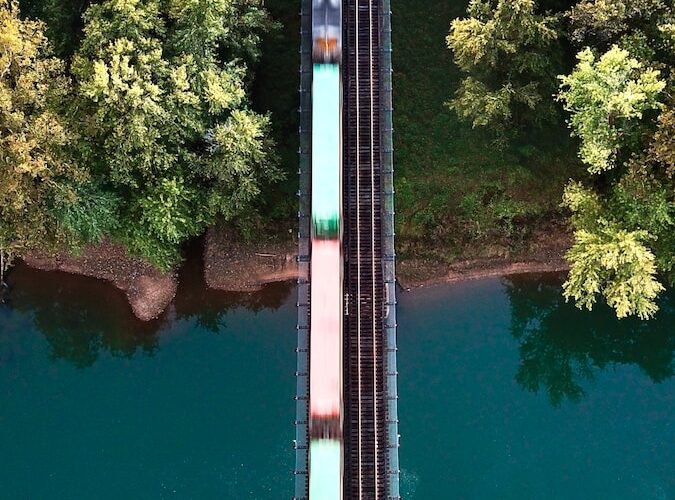 a train traveling over a bridge next to a forest