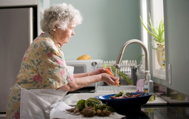 woman in purple and white floral shirt sitting on white bed